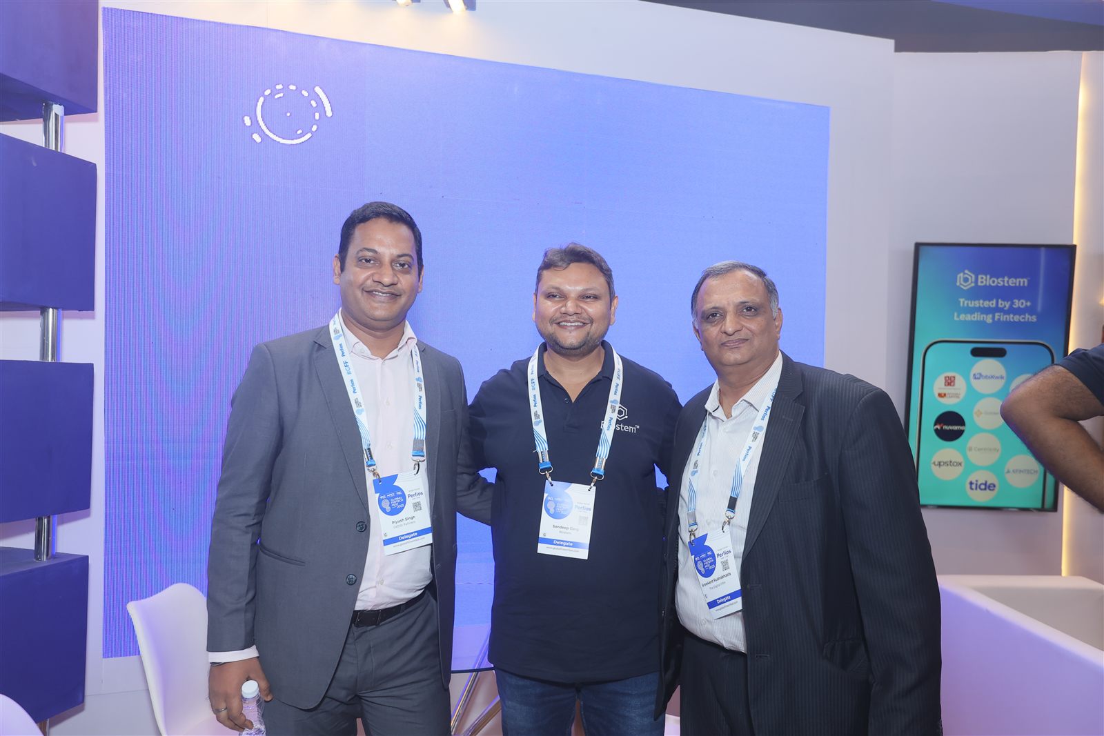 Guests at the Blostem booth beside the Trusted by 30+ Leading Fintechs screen